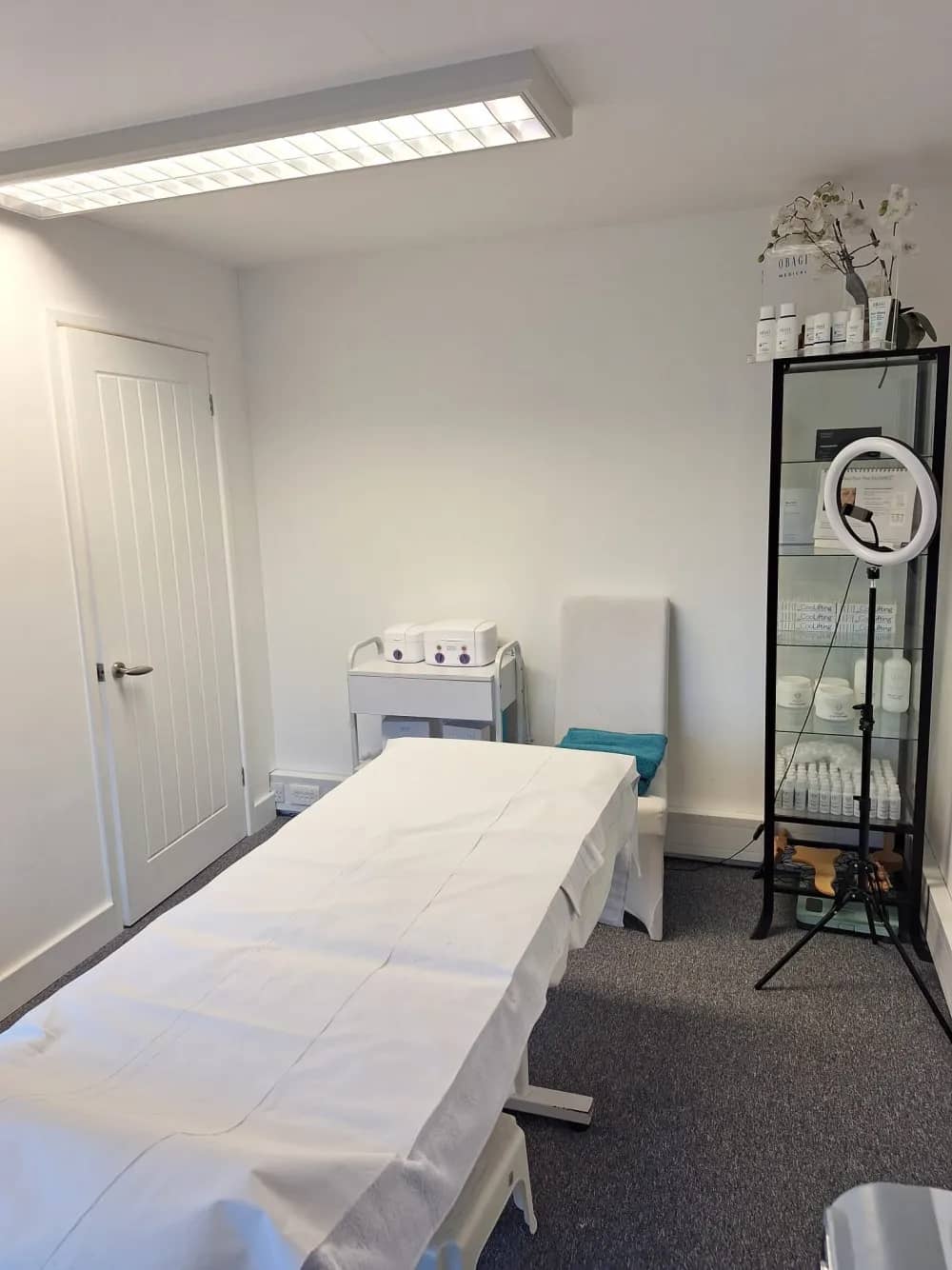 A treatment room at Laserlite Clinic — treatment bed, trolley and skincare cabinet A treatment room at Laserlite Clinic — treatment bed, trolley and skincare cabinet
