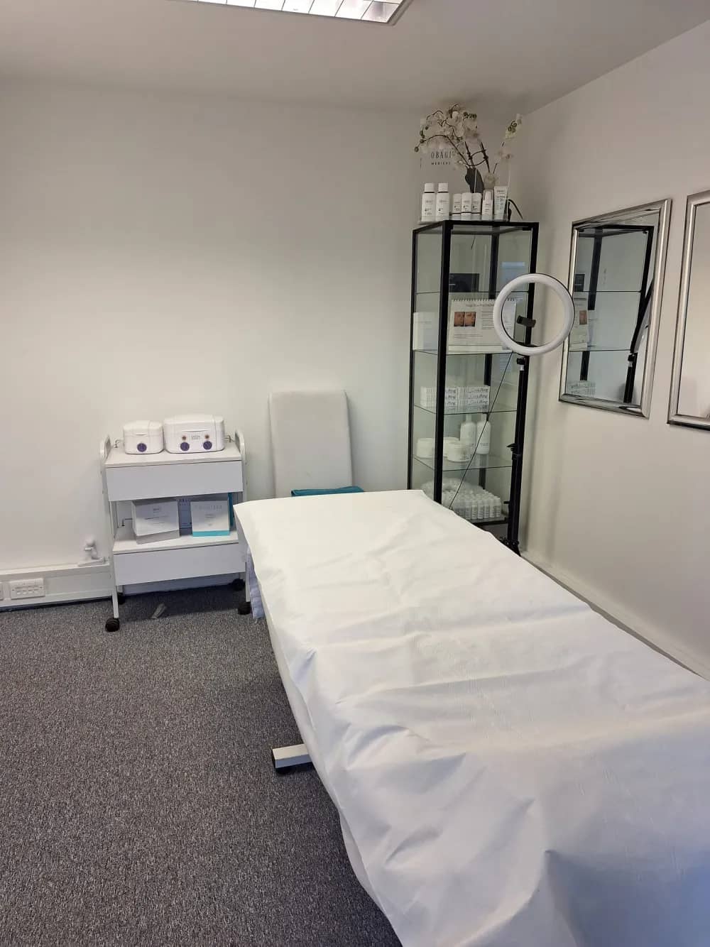 A treatment room at Laserlite Clinic with the Obagi skincare cabinet and ring light A treatment room at Laserlite Clinic with the Obagi skincare cabinet and ring light