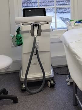 The clinic's laser machine by the window, beside a treatment couch The clinic's laser machine by the window, beside a treatment couch