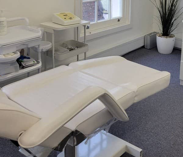 A white treatment chair, a trolley of equipment and a tall plant in one of the clinic's treatment rooms A white treatment chair, a trolley of equipment and a tall plant in one of the clinic's treatment rooms