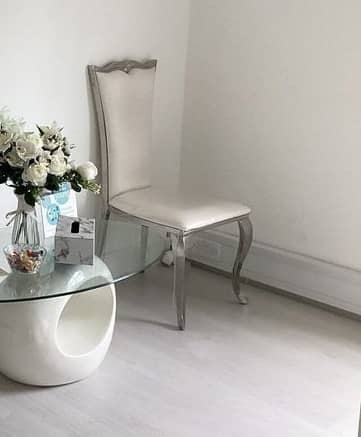 A white chair beside a glass table with white flowers in the clinic's waiting area A white chair beside a glass table with white flowers in the clinic's waiting area